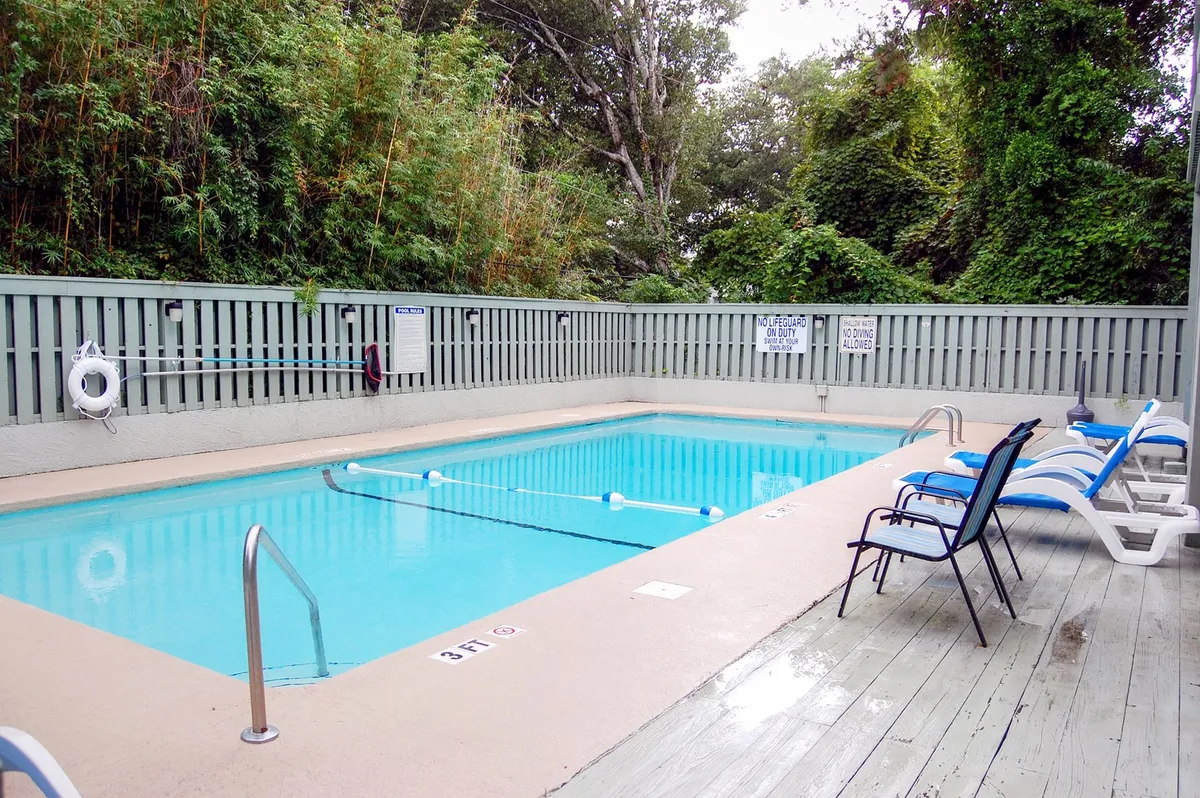 A sparkling swimming pool surrounded by lounge chairs and verdant landscaping. The pool area is tranquil, inviting, and suggests a resort-style environment, perfect for both relaxing swims and social gatherings.