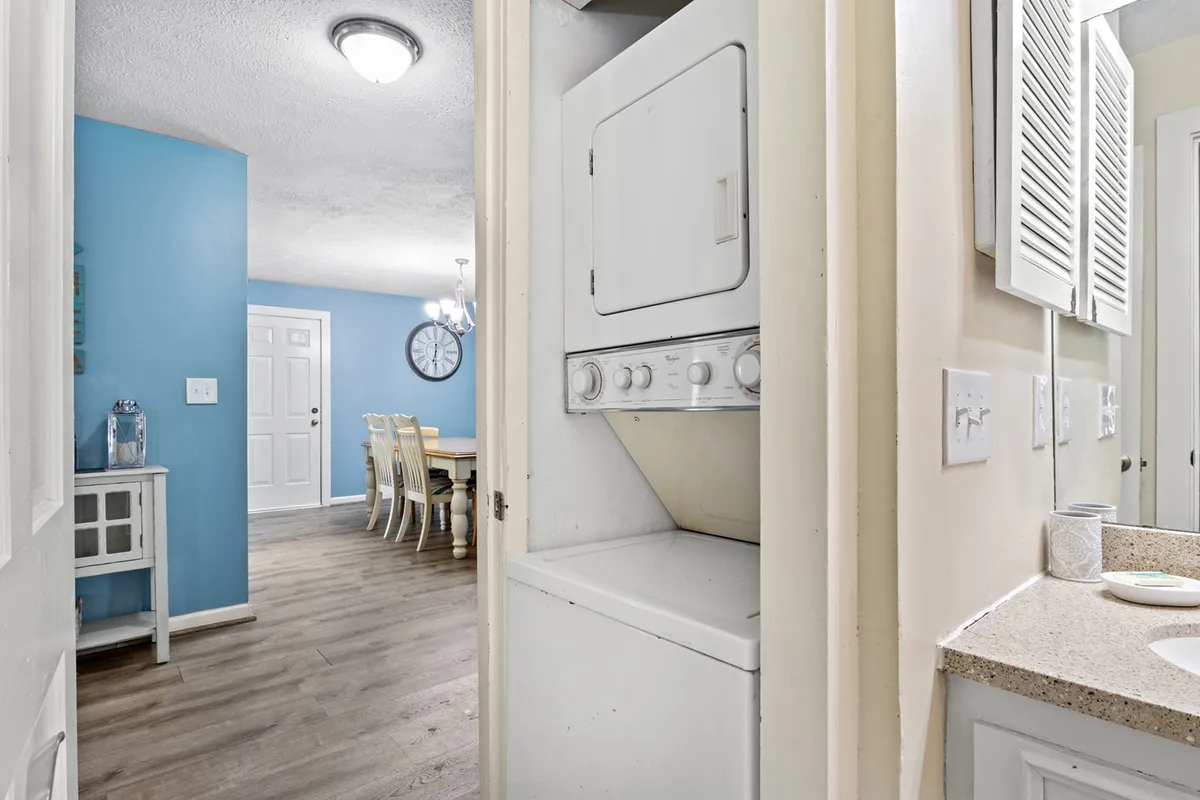 This image features a washer and dryer—integrated into the home—alongside a view of the dining area and a welcoming blue wall. The functional layout supports both meal times and practical needs for extended stays.