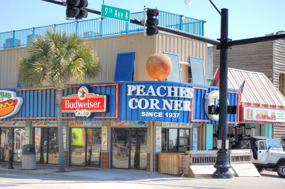 Featuring the iconic Peaches Corner sign, vibrant building facades, a palm tree, and lively street atmosphere, this image showcases Myrtle Beach’s festive dining and nightlife options. People can be seen dining and socializing, emphasizing the area’s entertainment value.
