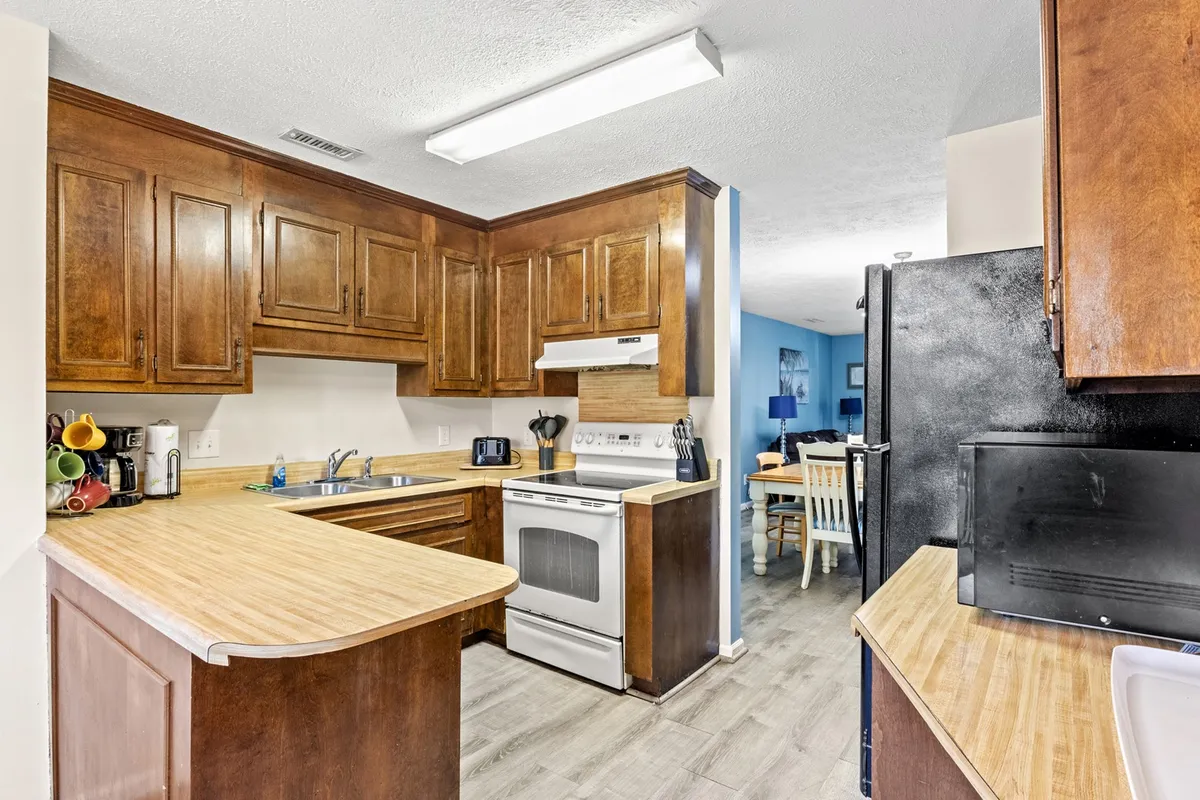 This image shows a cozy and functional kitchen with a prominent kitchen counter, oven, and cabinets, while the dining area is visible in the background. The scene suggests a space that's ideal for cooking, baking, or entertaining family and friends.